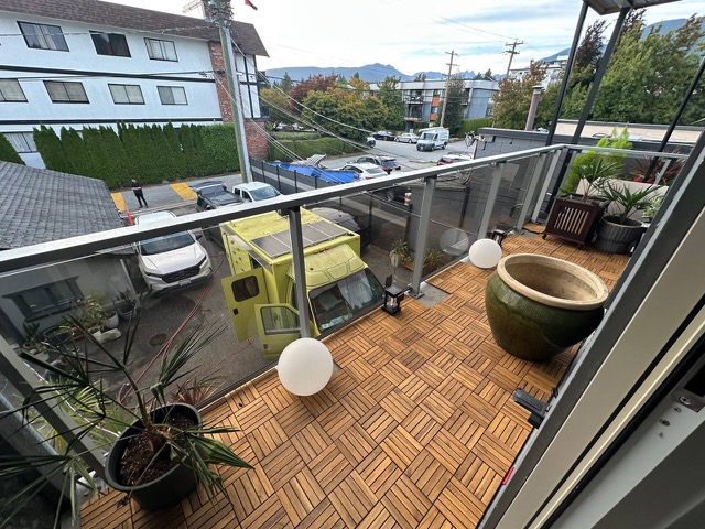 Balcony with deck tiles, a large green planter and globe lights, looking over the street