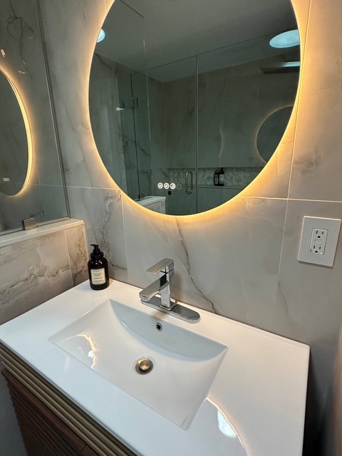 Sink and backlit round mirror in the second bathroom