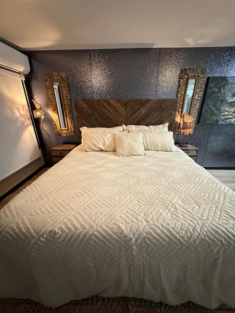 Second bedroom with king bed, wood headboard and gold mirrors