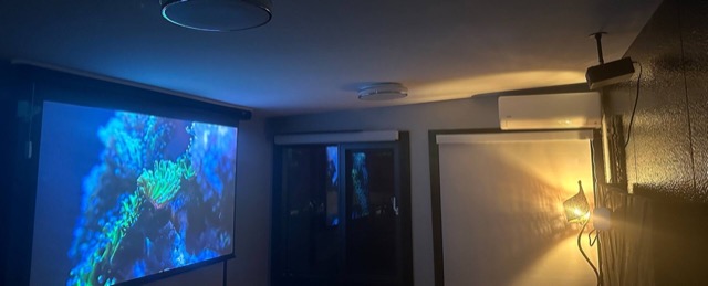 Second bedroom at night with the pull-down projector screen, air conditioning and a rattan wall lamp