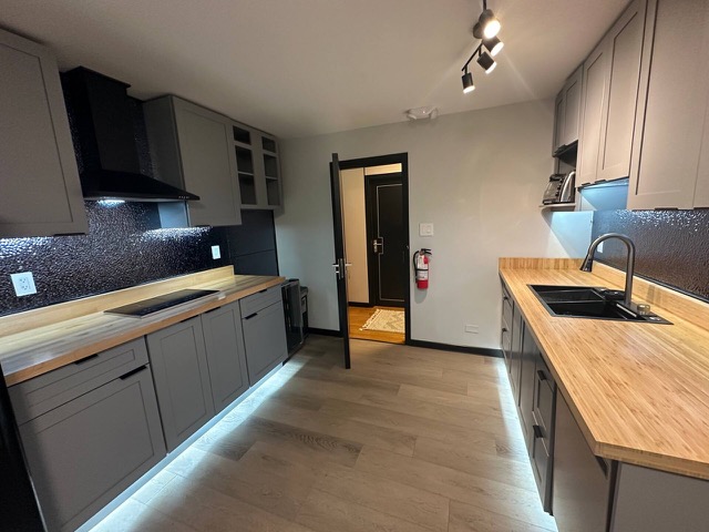 Kitchen with butcher-block counters and under-cabinet lighting, the hallway door open
