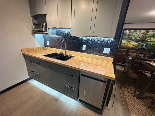 Butcher-block sink counter with a mosaic backsplash and under-cabinet lighting