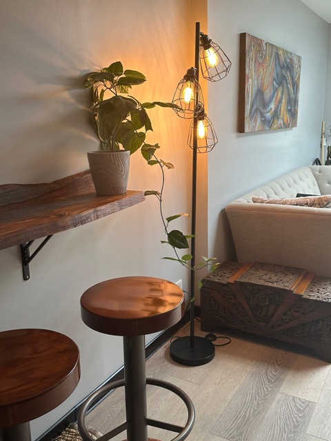 Bar stools at a floating wood table, with a floor lamp